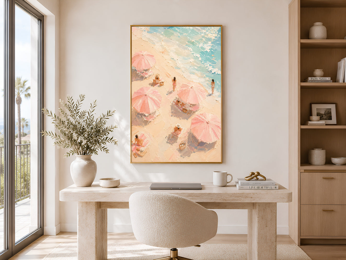 Pink beach umbrella coastal print in gold frame displayed in a calm neutral home office with round desk and open shelving