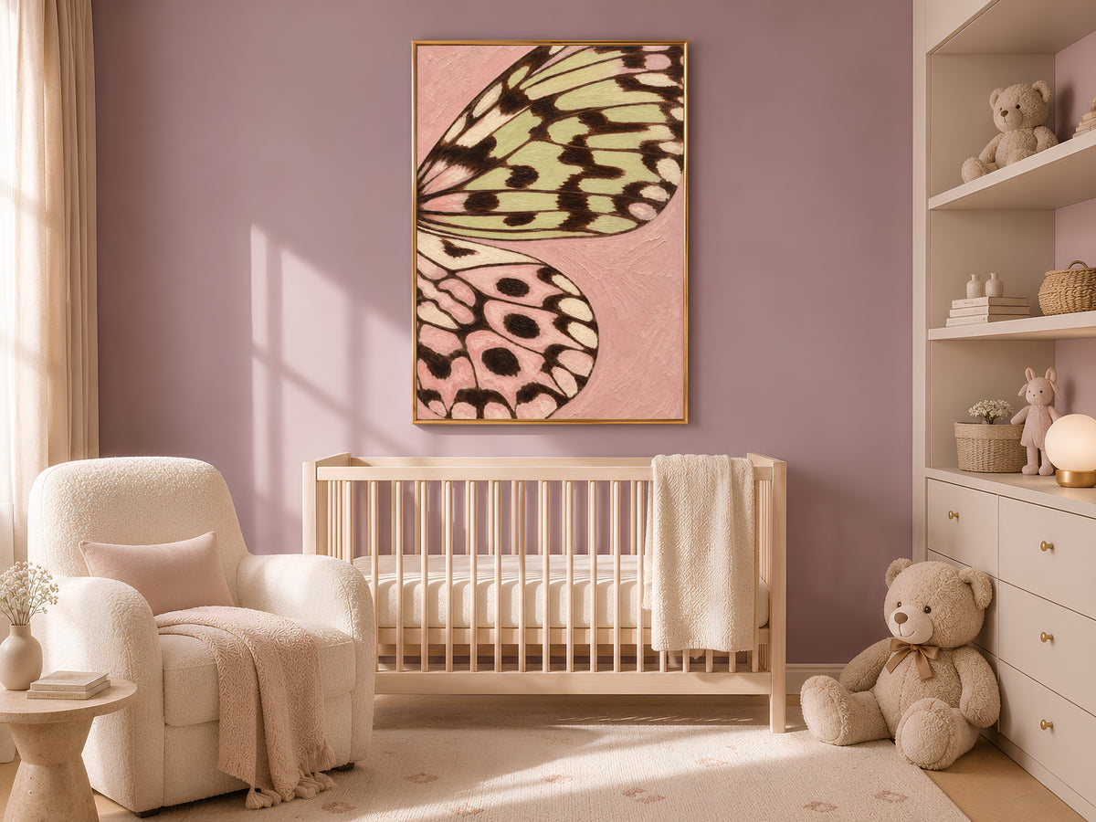 Pink and sage green butterfly wing art framed above a crib in a soft neutral nursery