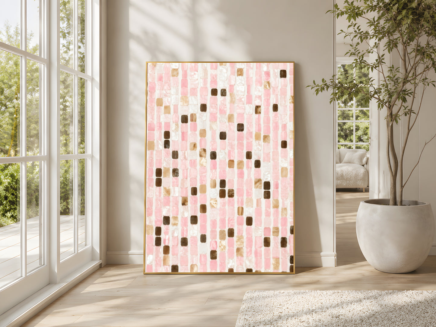 Blush pink mosaic tile print in gold frame beside floor-to-ceiling windows in bright Mediterranean living room with large indoor plant and warm natural light