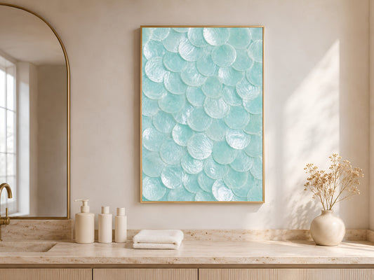 Seafoam capiz shell print in a gold frame hung above a bathroom vanity with white towels and ceramic accessories.