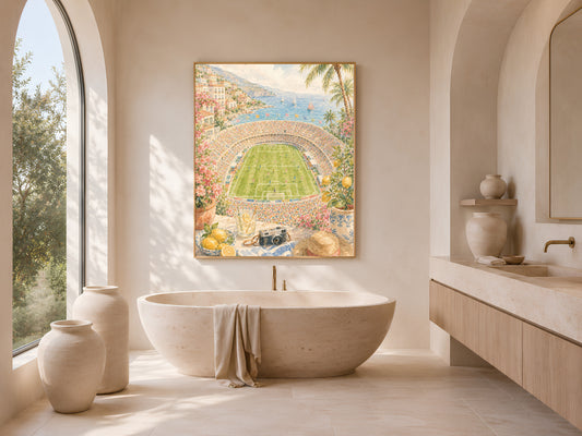 Bright bathroom with arched window and freestanding soaking tub, framed watercolor soccer stadium print hanging beside a small round side table.