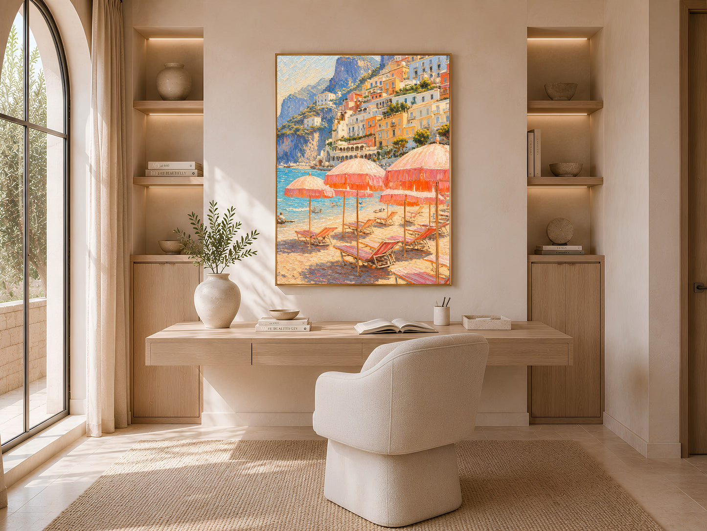 Sunlit reading nook with curved built-in shelving and a cushioned chair, framed Positano coastal wall art displayed above a wooden desk.

