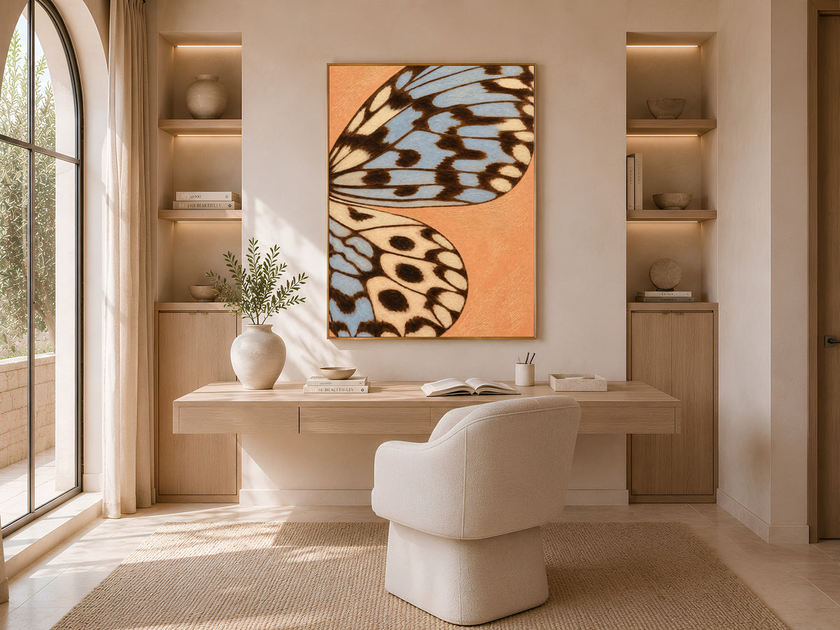 Terracotta blue butterfly wing print framed above a console in a warm neutral reading nook