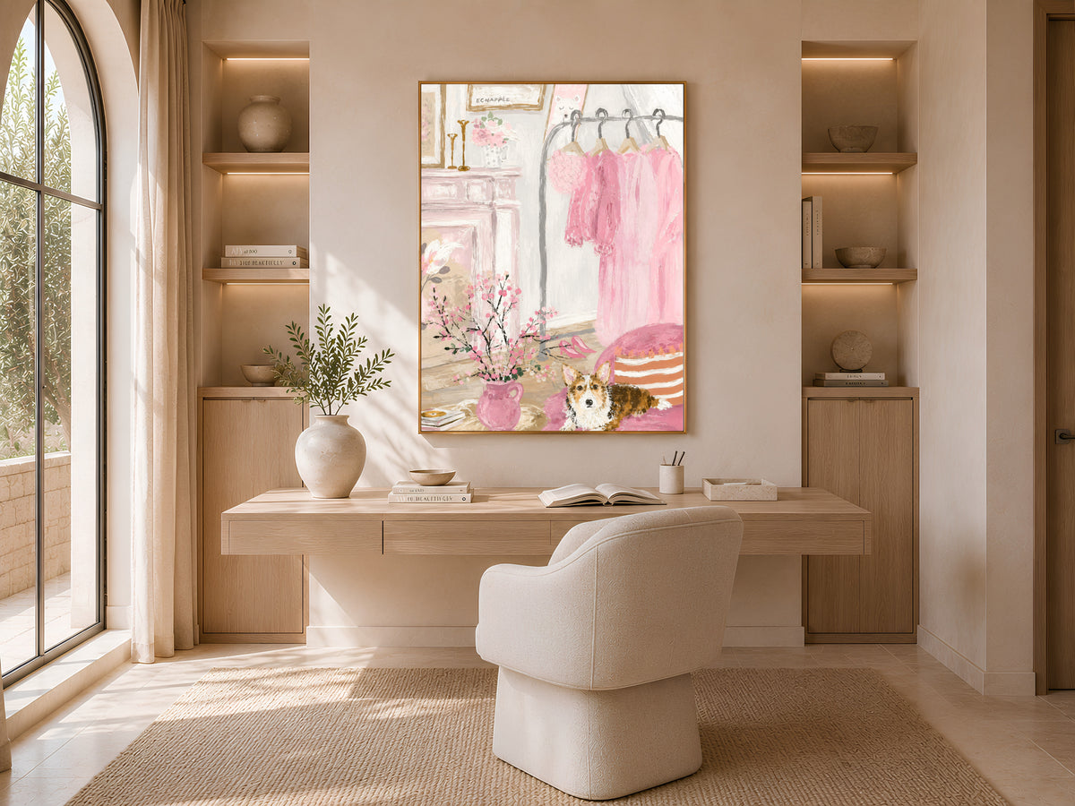 Pink closet illustration framed in gold above a walk-in closet desk nook with a boucle chair