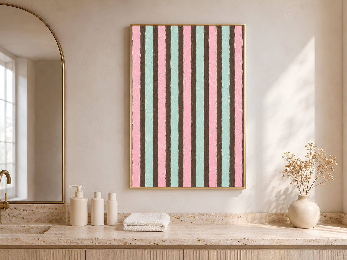 Pink mint stripe wall art in gold frame in bright neutral bathroom with arched niche and white towels
