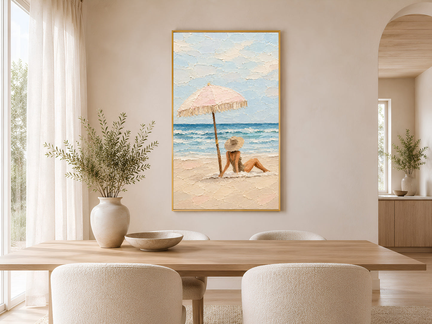 Framed pastel beach scene impasto print on wall in a warm neutral dining room with round wooden table, linen chairs, and dried botanicals
