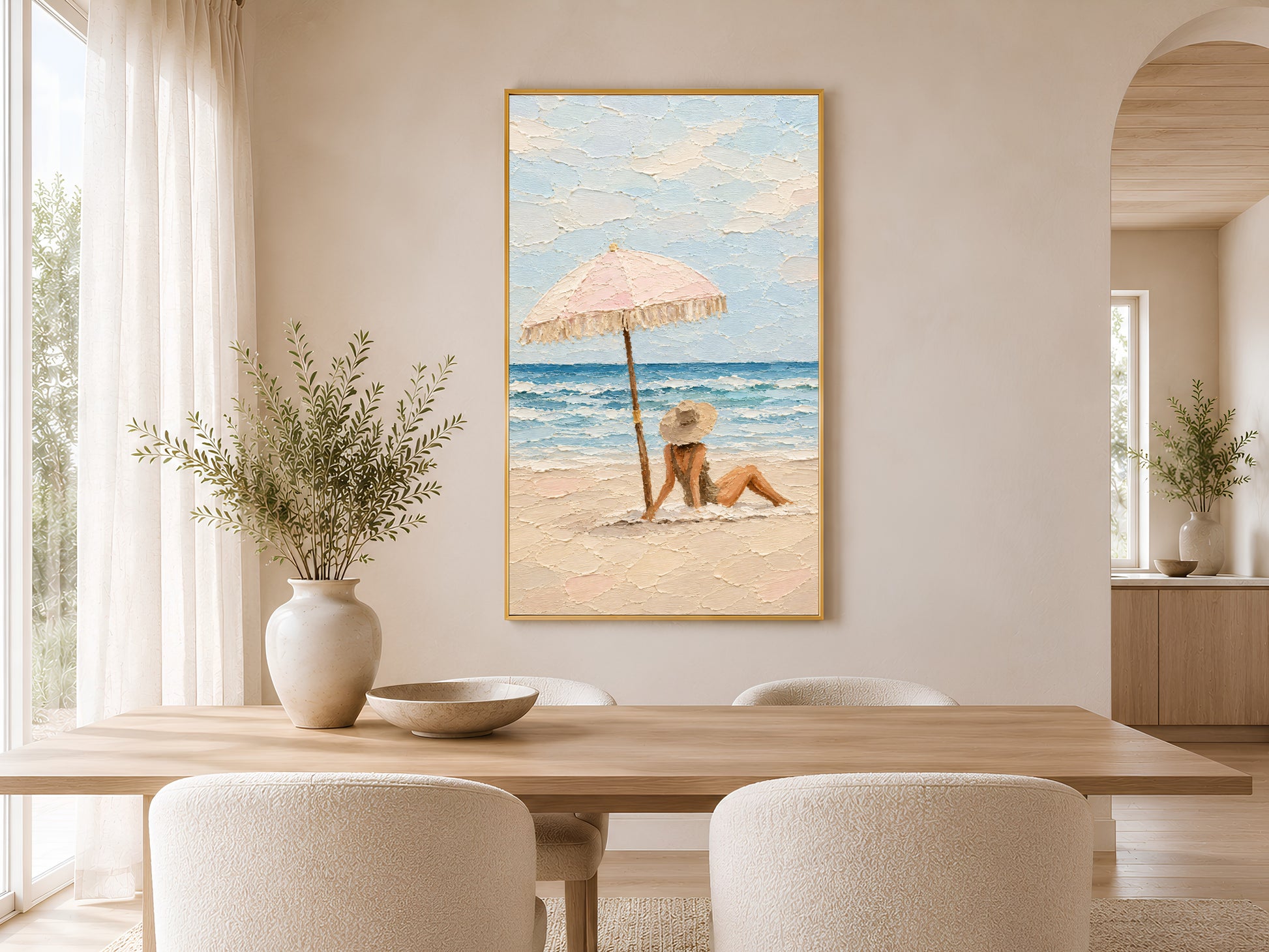 Framed pastel beach scene impasto print on wall in a warm neutral dining room with round wooden table, linen chairs, and dried botanicals
