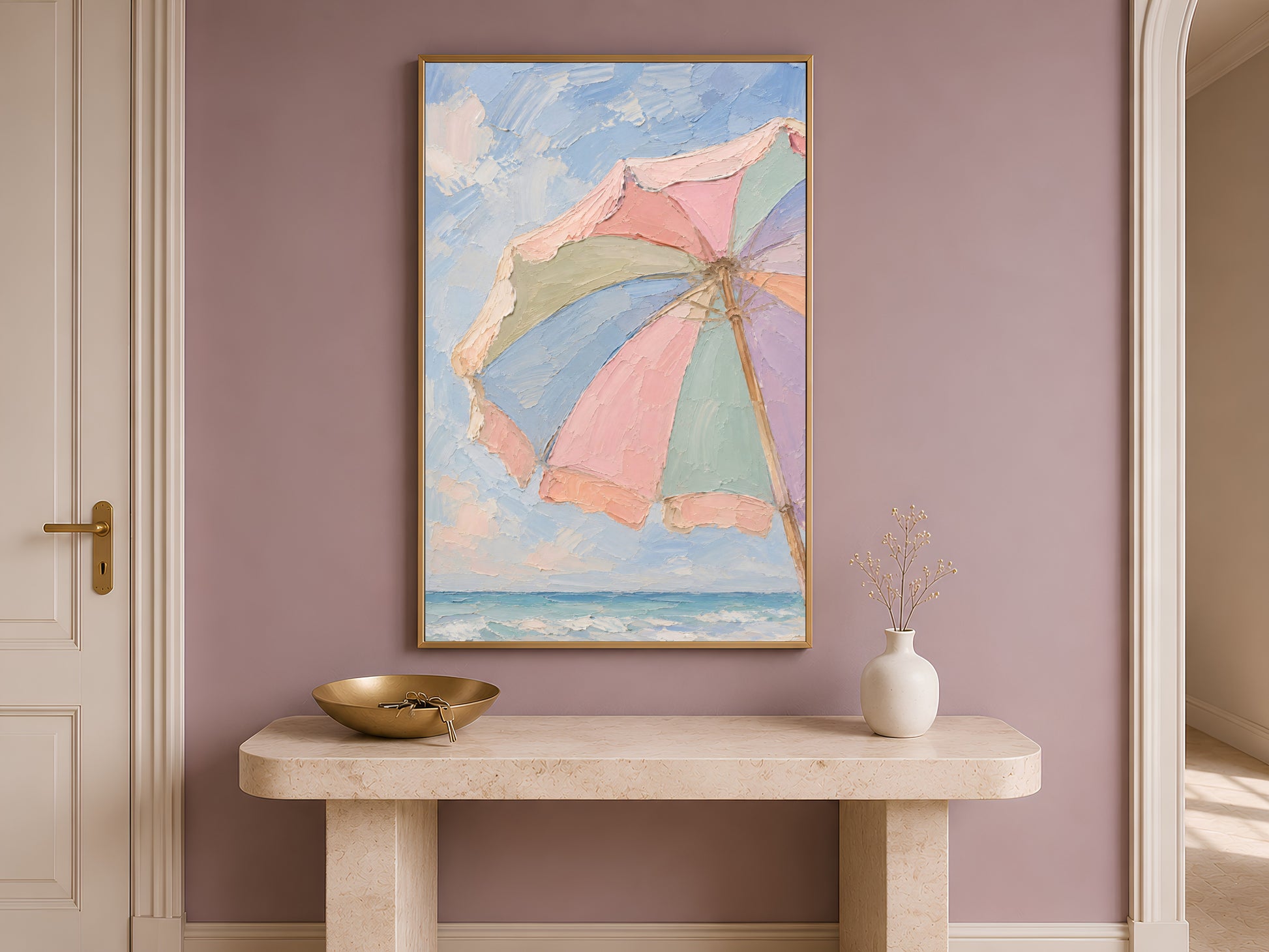 Beach umbrella print framed in gold displayed above console table in bright neutral entryway
