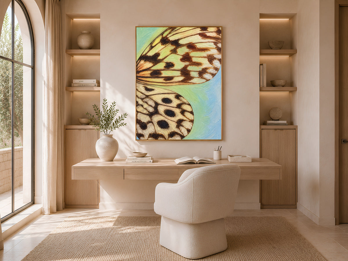 Teal gradient butterfly wing print framed above a desk in a sunlit home office