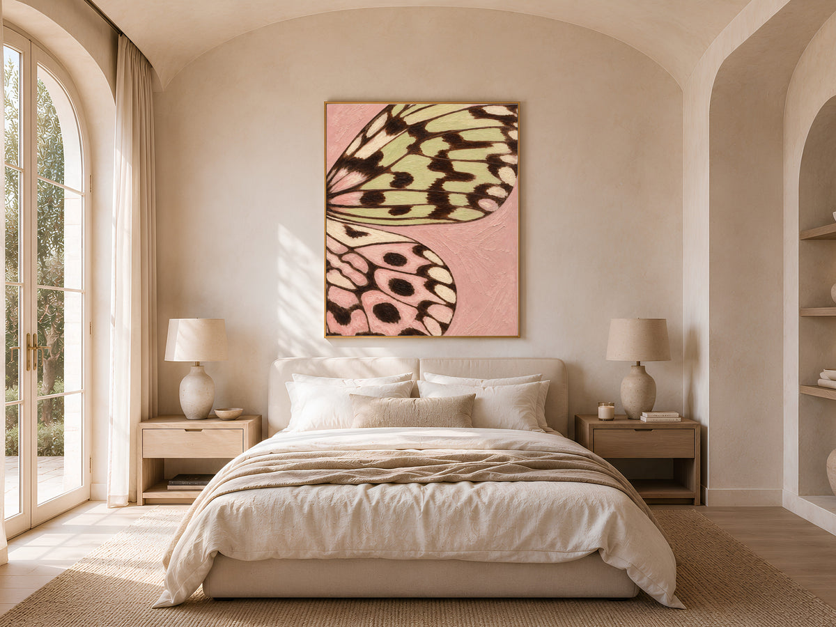 Framed butterfly wing print above a bed near an arched window in a bright, airy bedroom