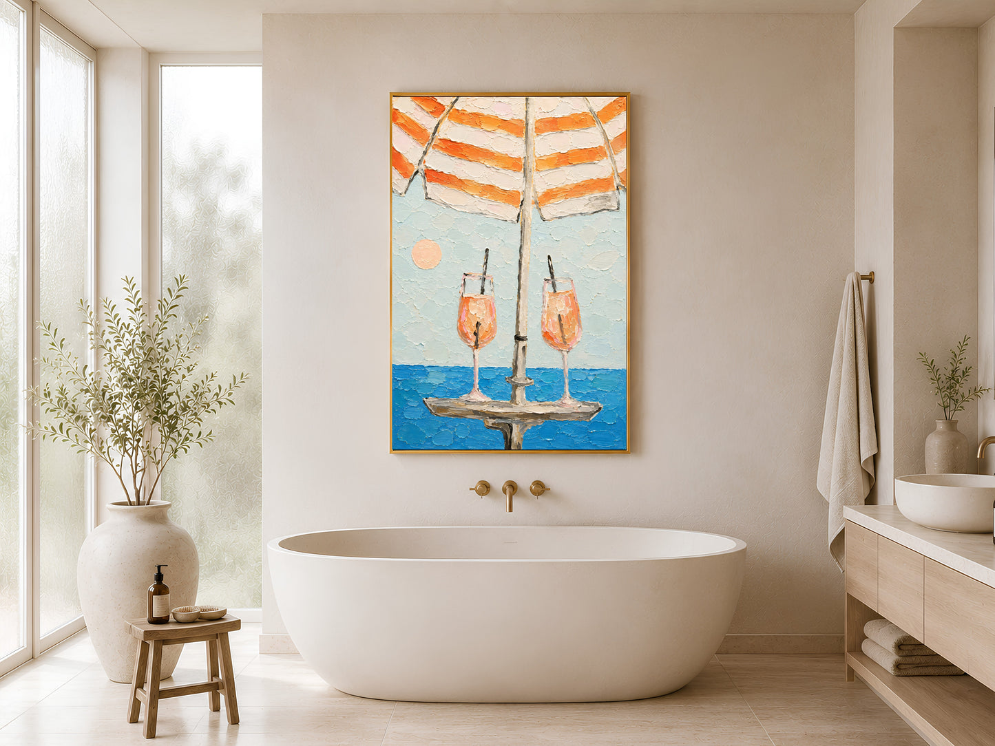 Framed aperol spritz impasto wall art beside a freestanding white soaking bathtub in a minimal spa bathroom with warm beige walls and gold fixtures
