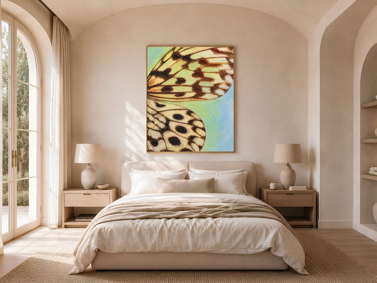 Framed teal blue gradient butterfly wing art hung above a bed in a bright, arched bedroom