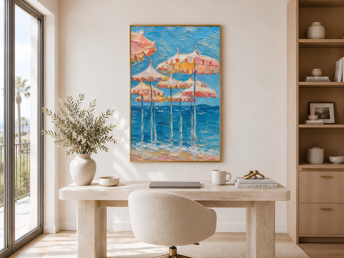 Gold-framed pink parasol coastal impasto print displayed in a minimalist home office with a light wood desk, neutral shelving, and greenery
