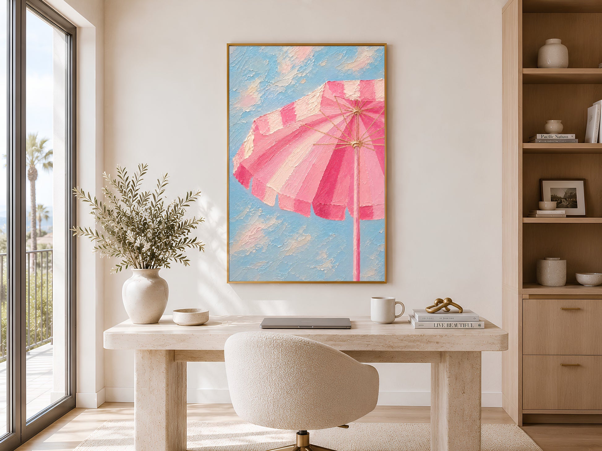 Framed pink striped beach umbrella painting print in a warm neutral living room with round dining table, curved chairs and olive stems

