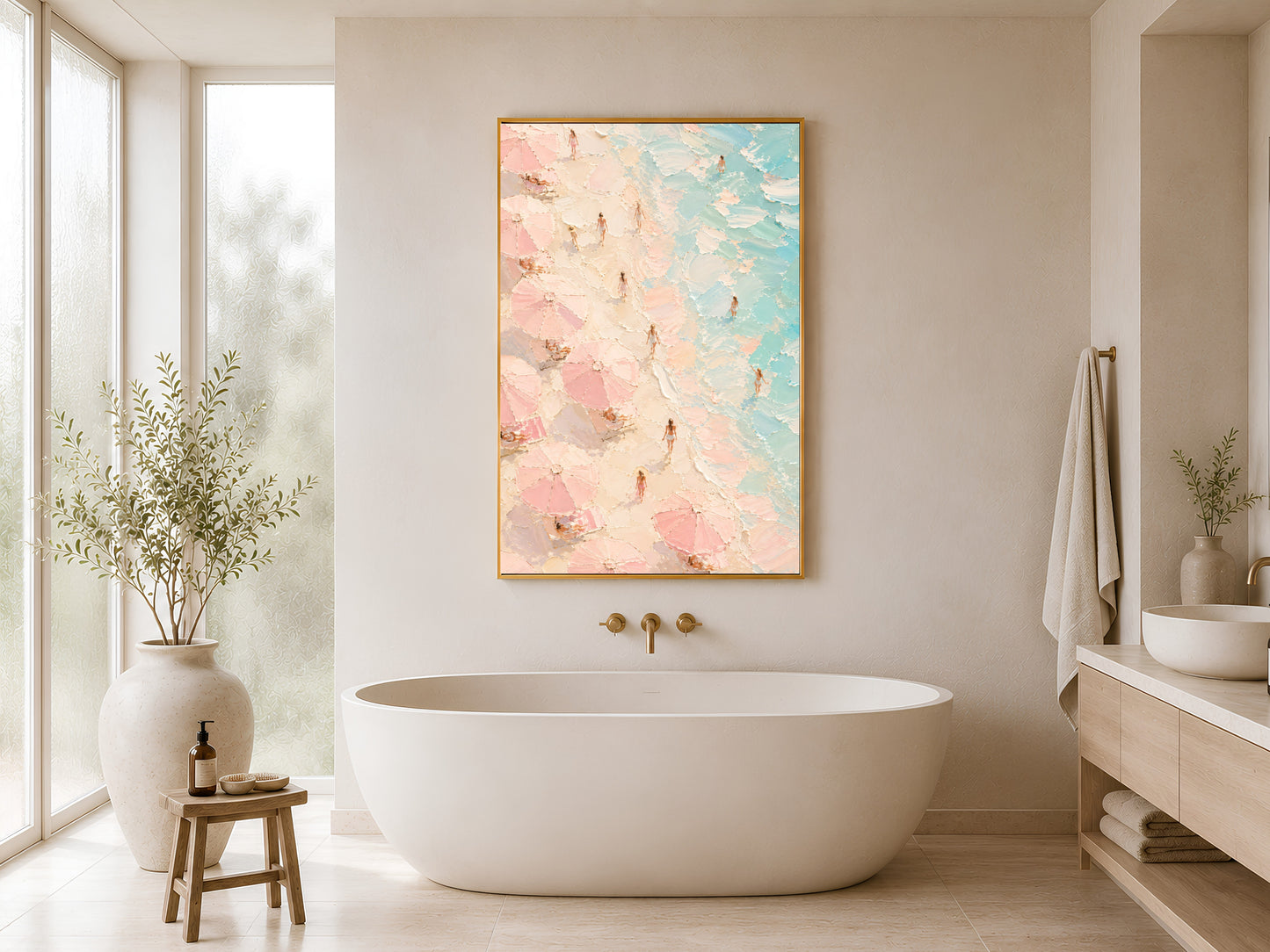 Framed aerial beach wall art in blush pink and teal styled in a minimal white bathroom beside a freestanding bathtub and warm wood stool
