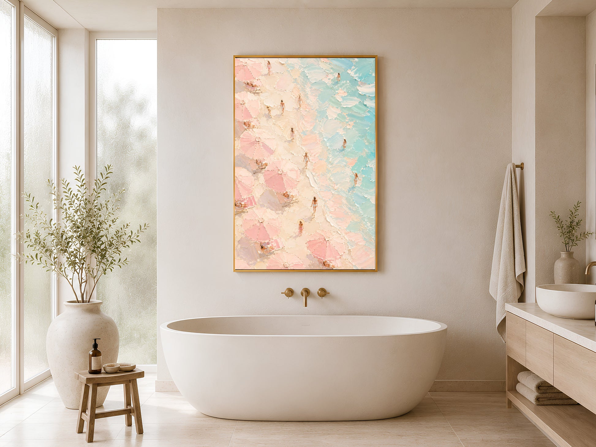 Framed aerial beach wall art in blush pink and teal styled in a minimal white bathroom beside a freestanding bathtub and warm wood stool
