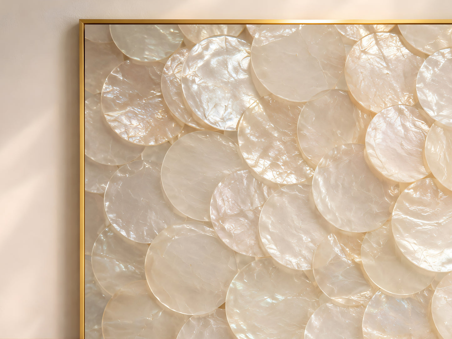 Close-up detail of luminous capiz shell wall art showing overlapping pearl shell discs with soft iridescent texture and creamy neutral tones.