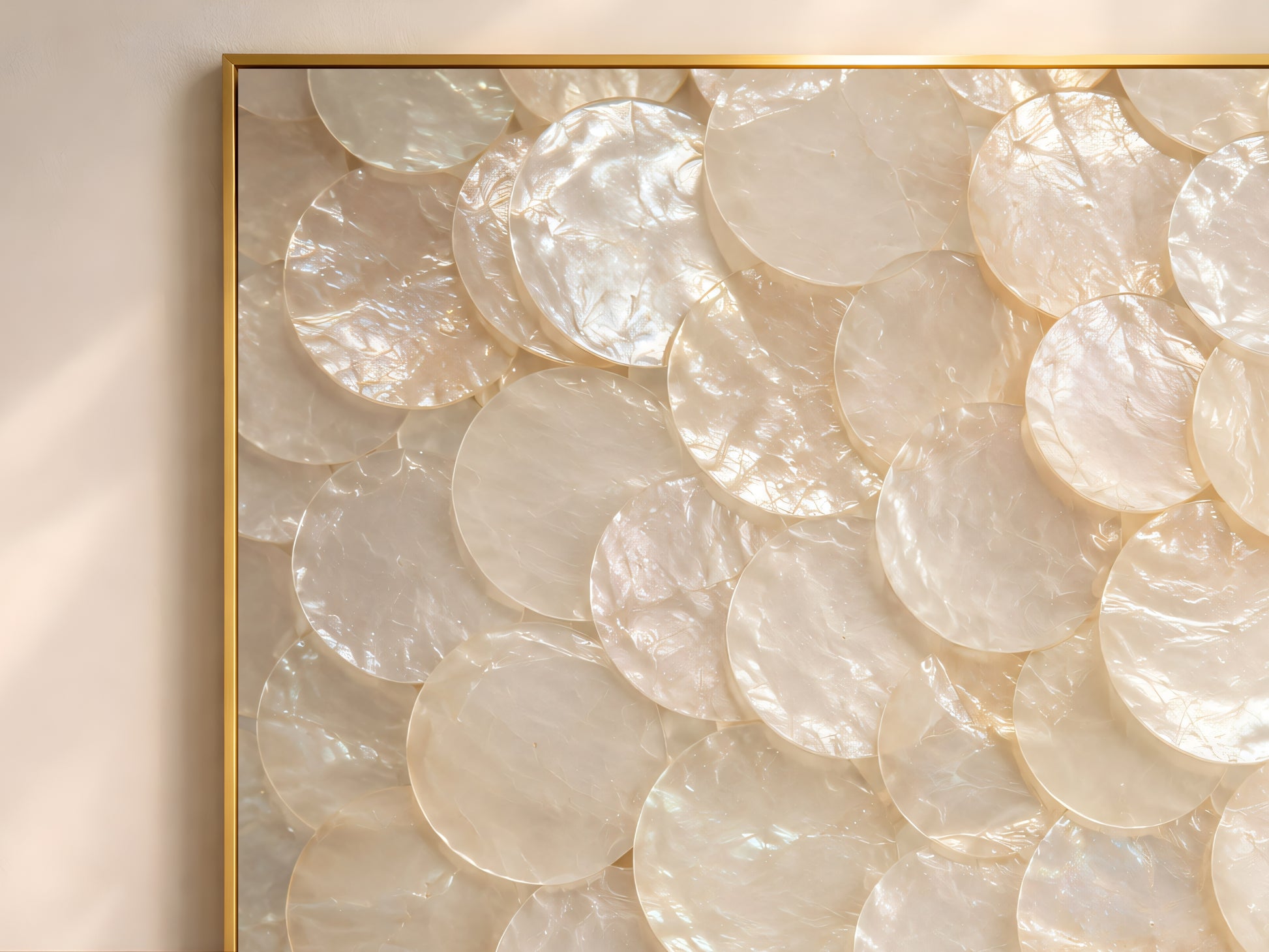 Close-up detail of luminous capiz shell wall art showing overlapping pearl shell discs with soft iridescent texture and creamy neutral tones.
