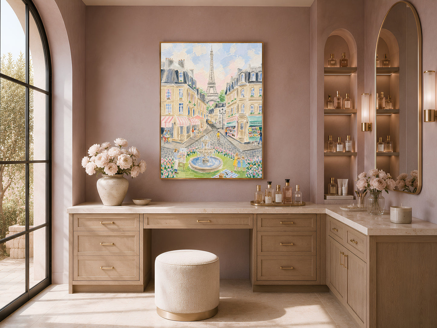 Impasto Paris street scene wall art in a gold frame above a vanity desk with white flowers and a cream ottoman in a warm minimal dressing room with large windows
