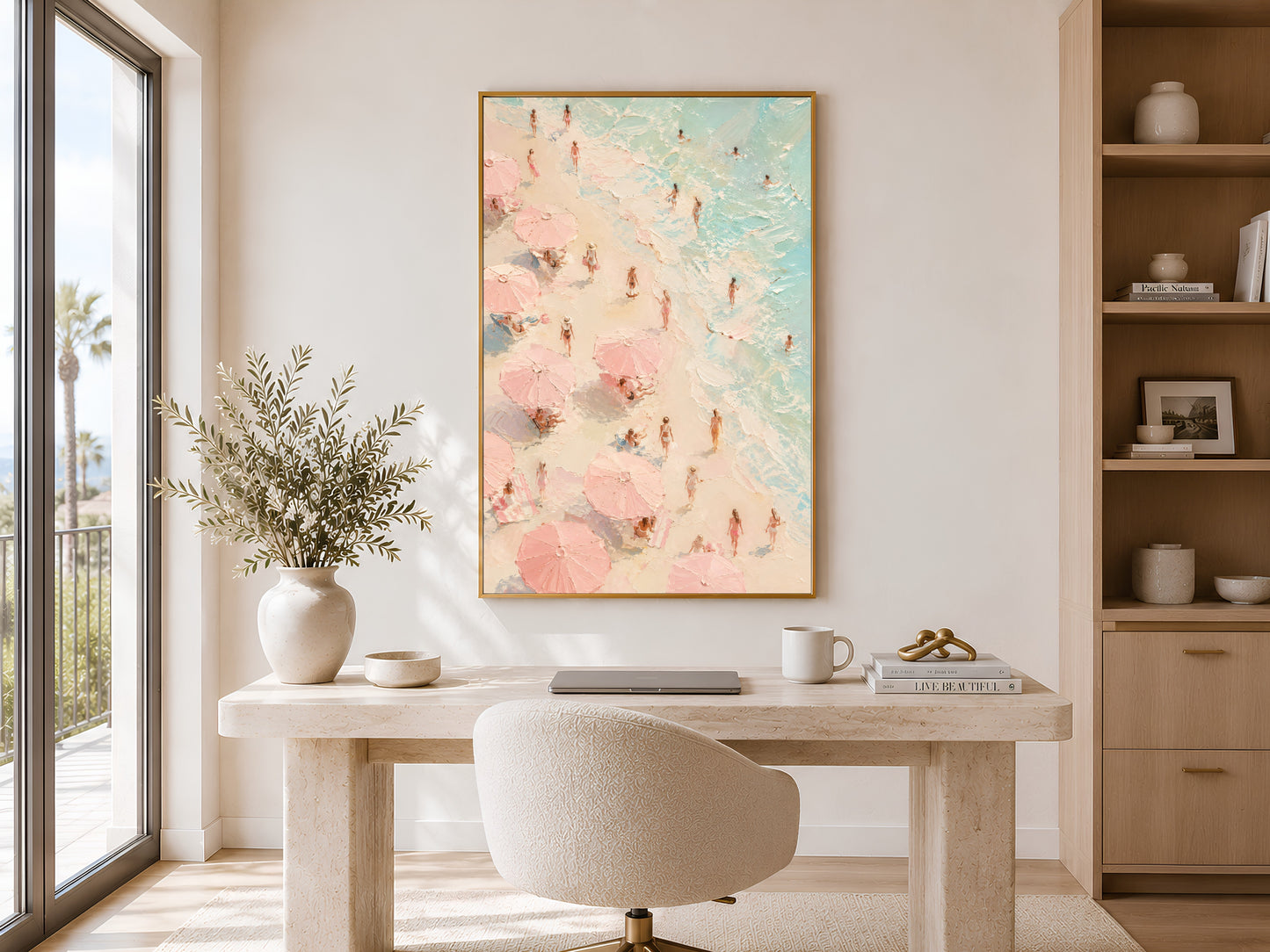 Aerial beach figures oil painting in gold frame displayed in a calm neutral home office with round desk and open shelving