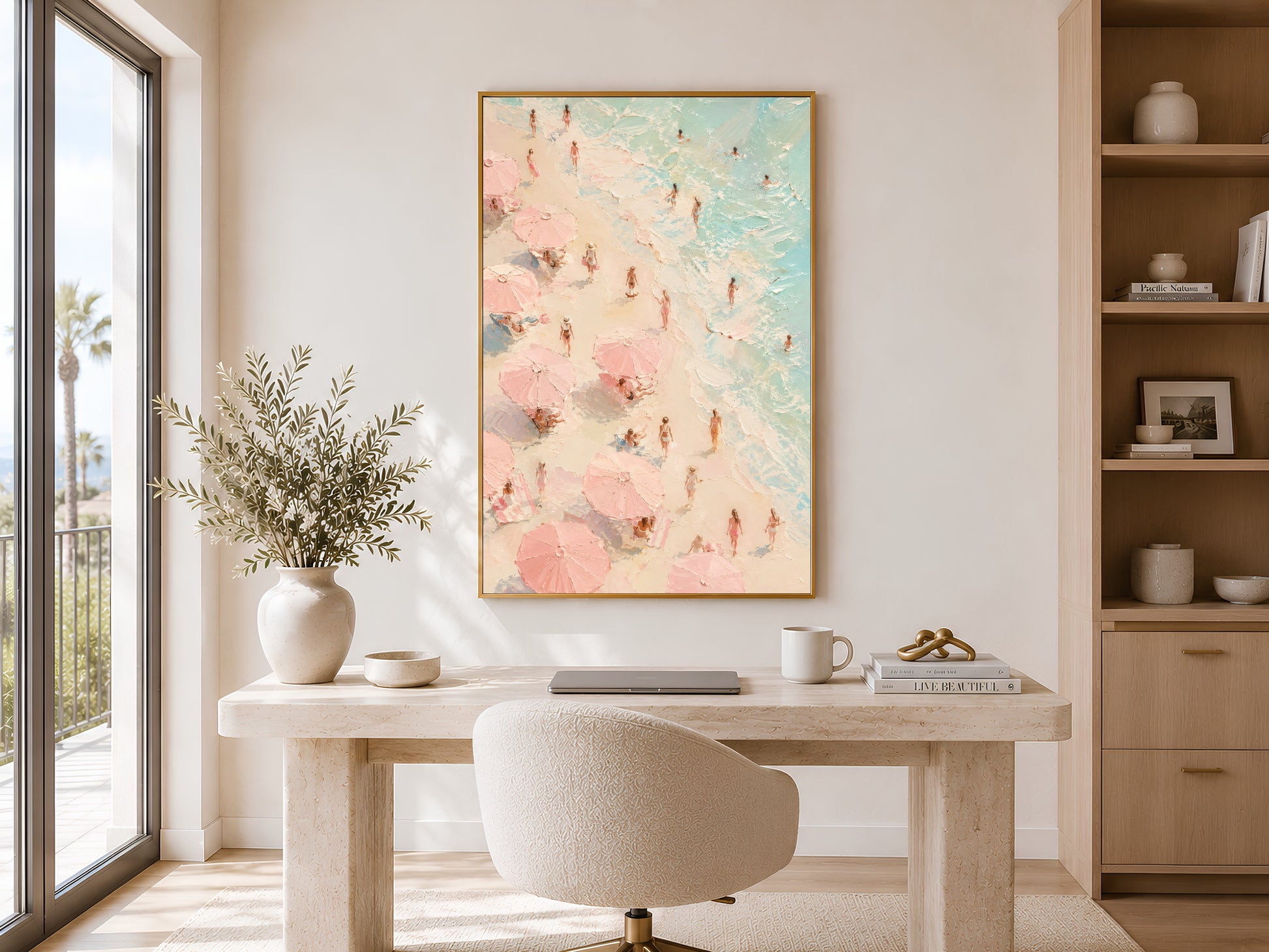 Aerial beach figures oil painting in gold frame displayed in a calm neutral home office with round desk and open shelving