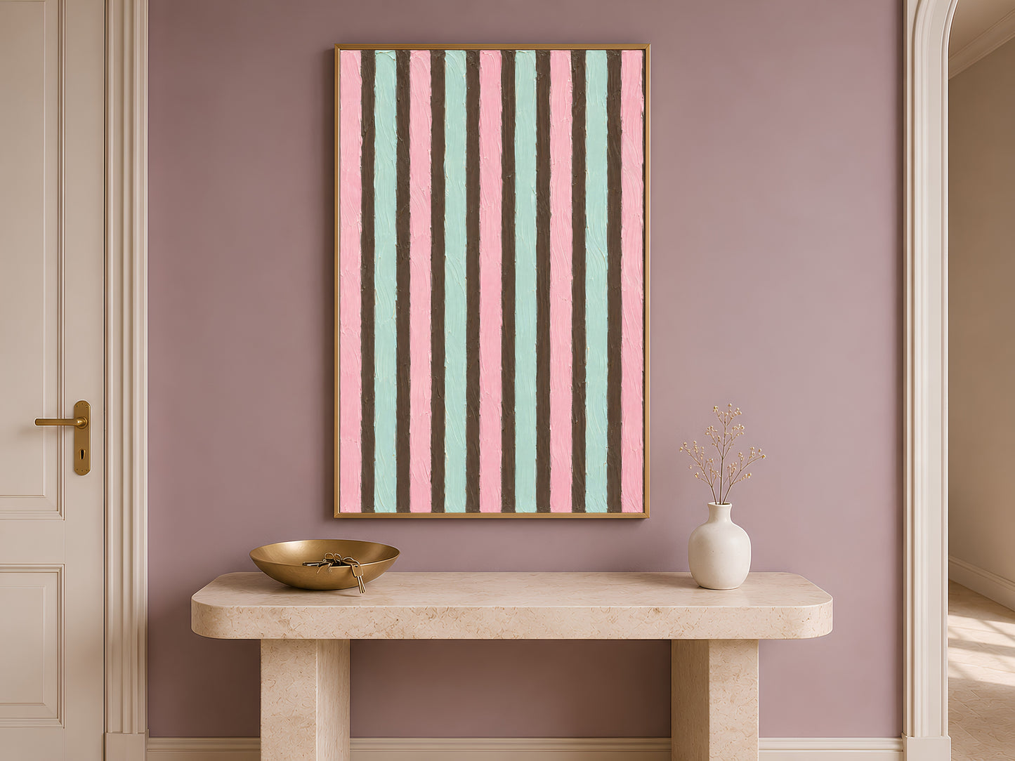 Pink mint stripe print in gold frame on travertine console table in hallway with white vases and warm lighting
