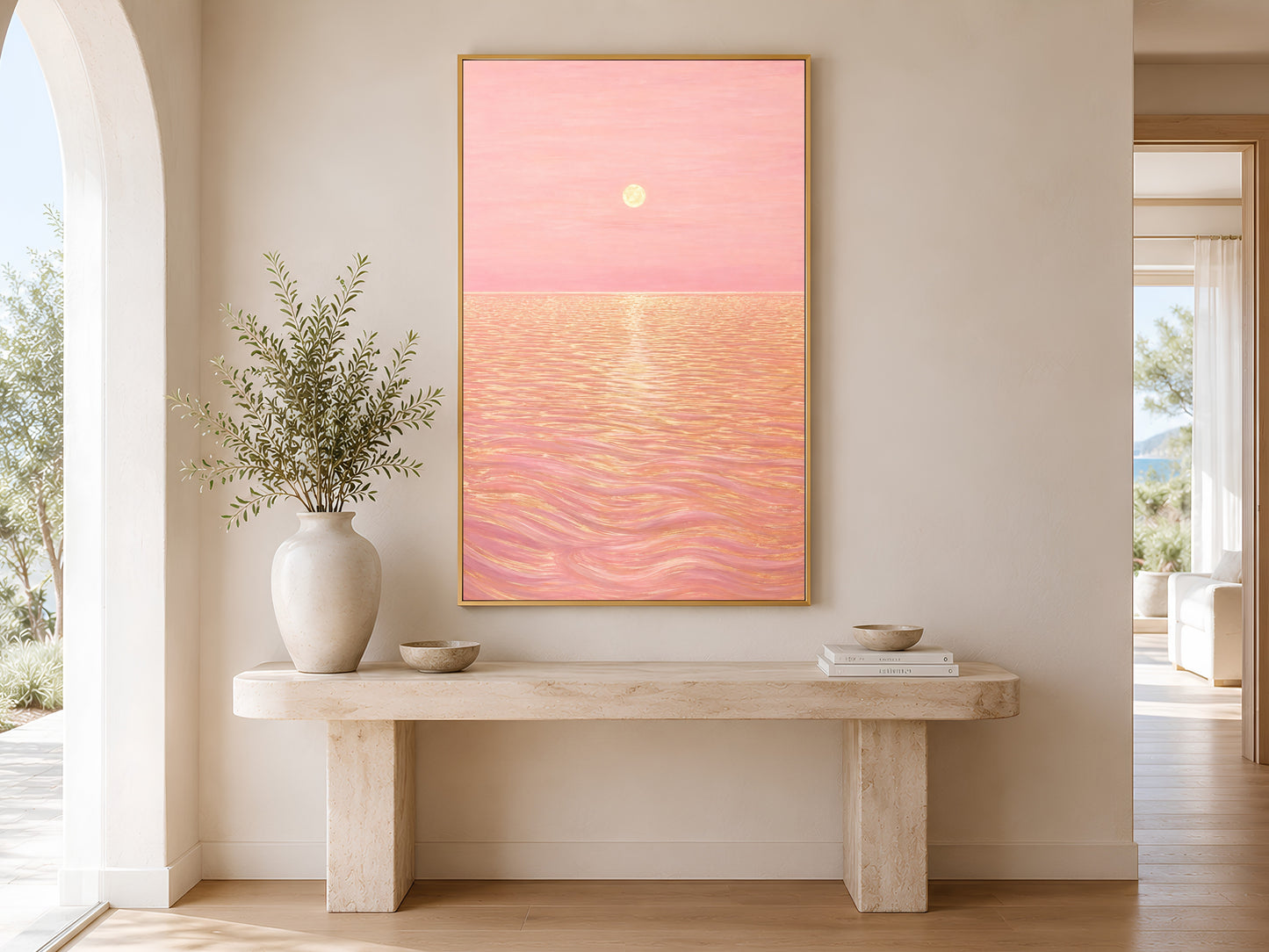 Pink sunset ocean print framed in gold hanging above a wooden entryway bench with plant
