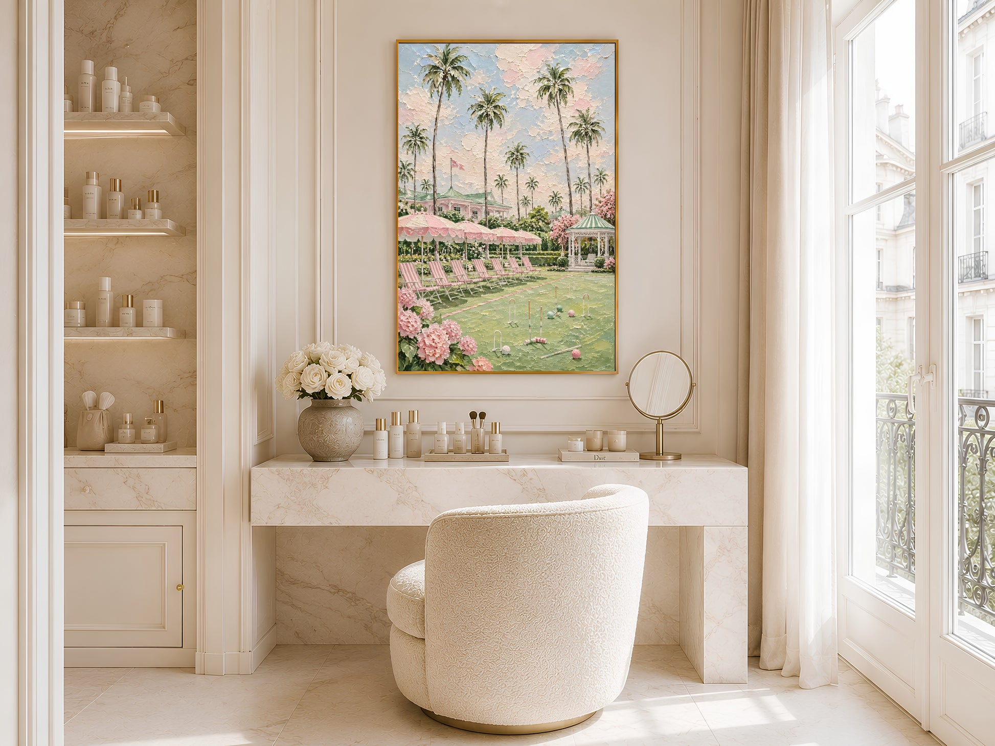 Gold-framed pink croquet lawn and palm tree impasto print in a bright bathroom beside a freestanding white bathtub with large windows and open shelving with flowers
