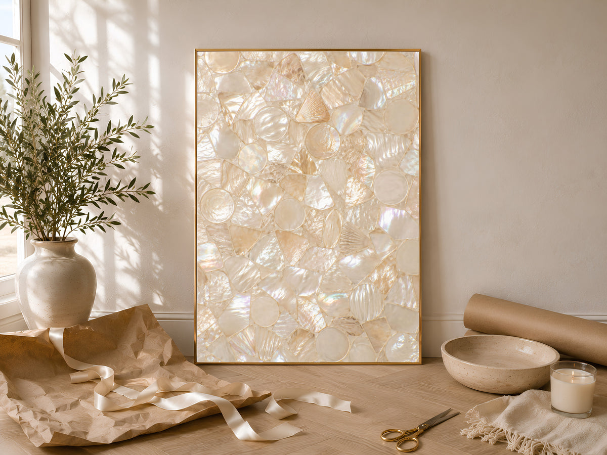 Framed mother of pearl mosaic print leaning on a sunlit console table with vases and greenery