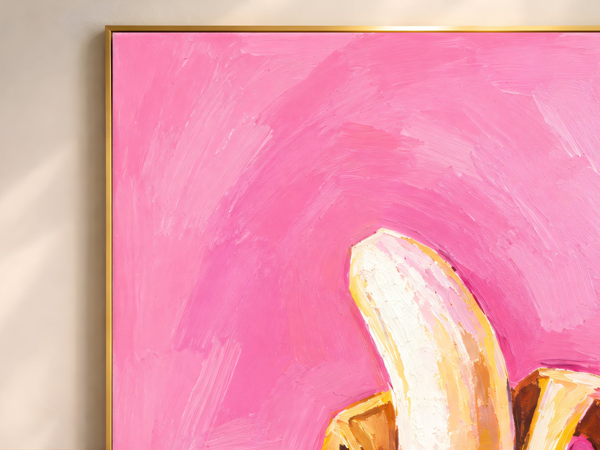 Framed impasto peeled banana wall art in gold frame on warm white wall showing full hot pink background and golden yellow banana
