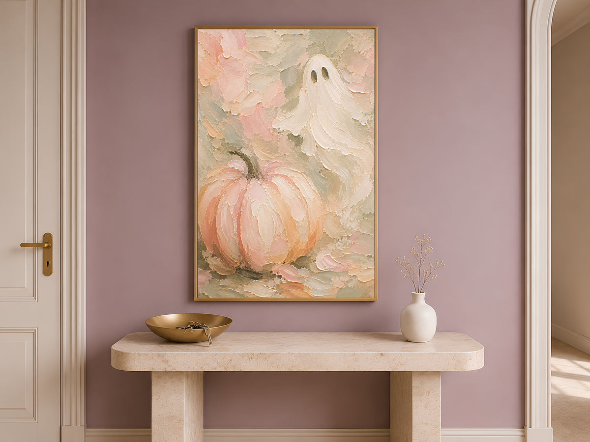Pastel ghost and pumpkin art print framed above a console table in a warm neutral entryway
