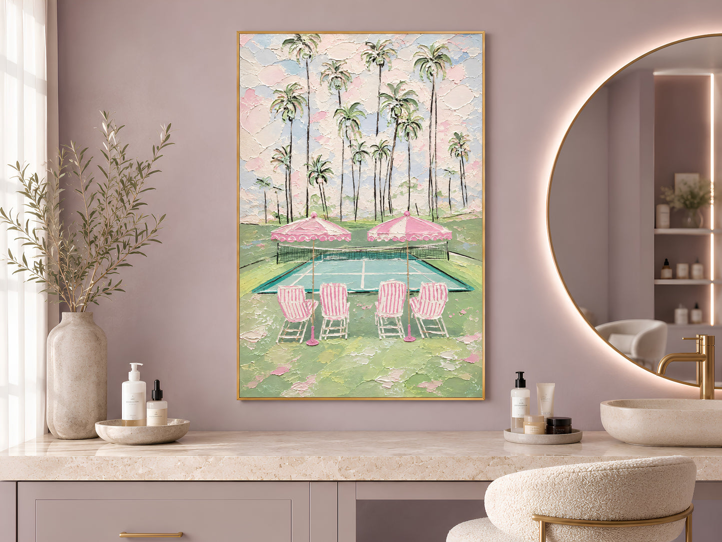 Pink tennis court print in gold frame beside round mirror in bathroom with dried flower arrangement

