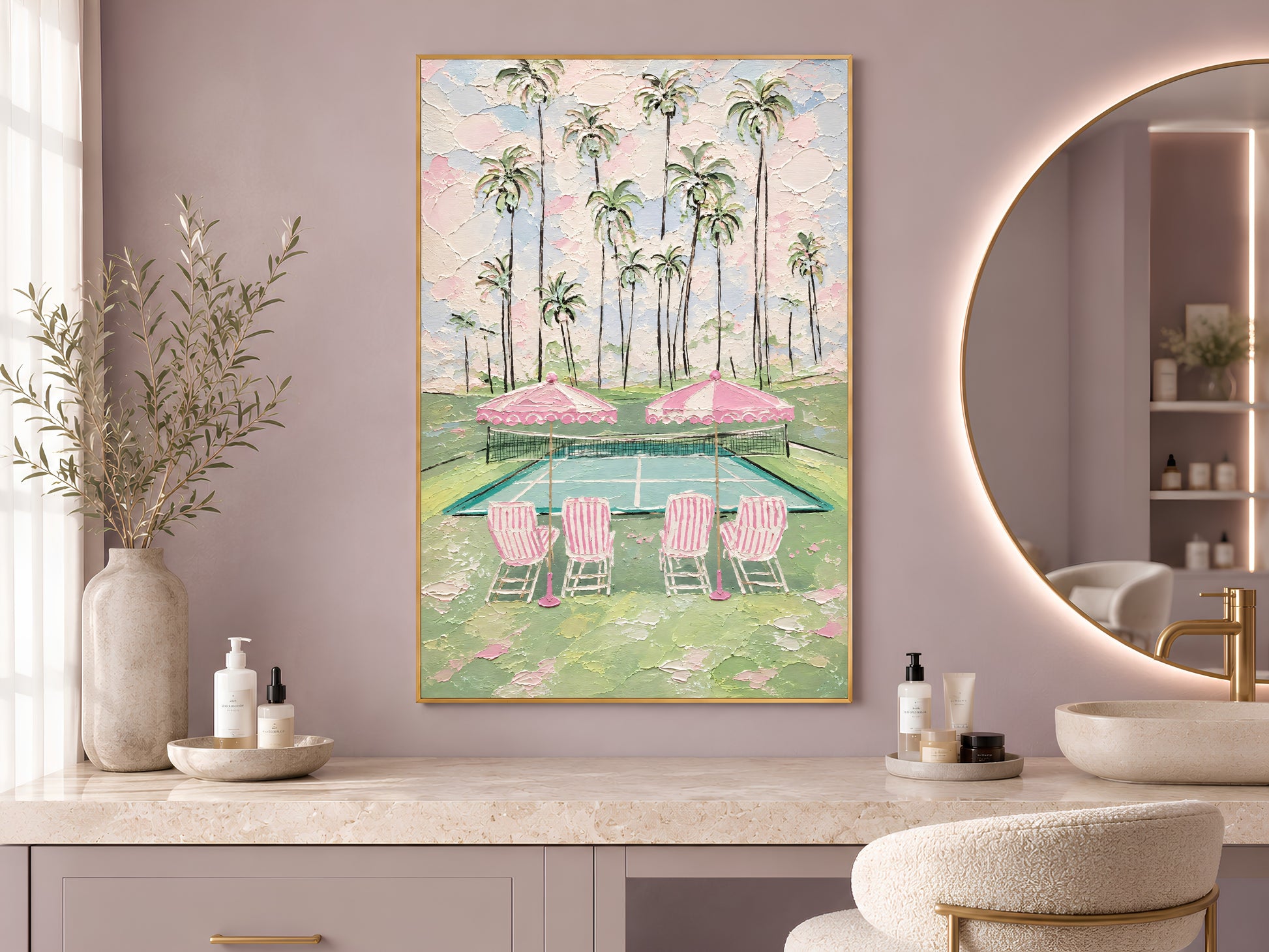 Pink tennis court print in gold frame beside round mirror in bathroom with dried flower arrangement
