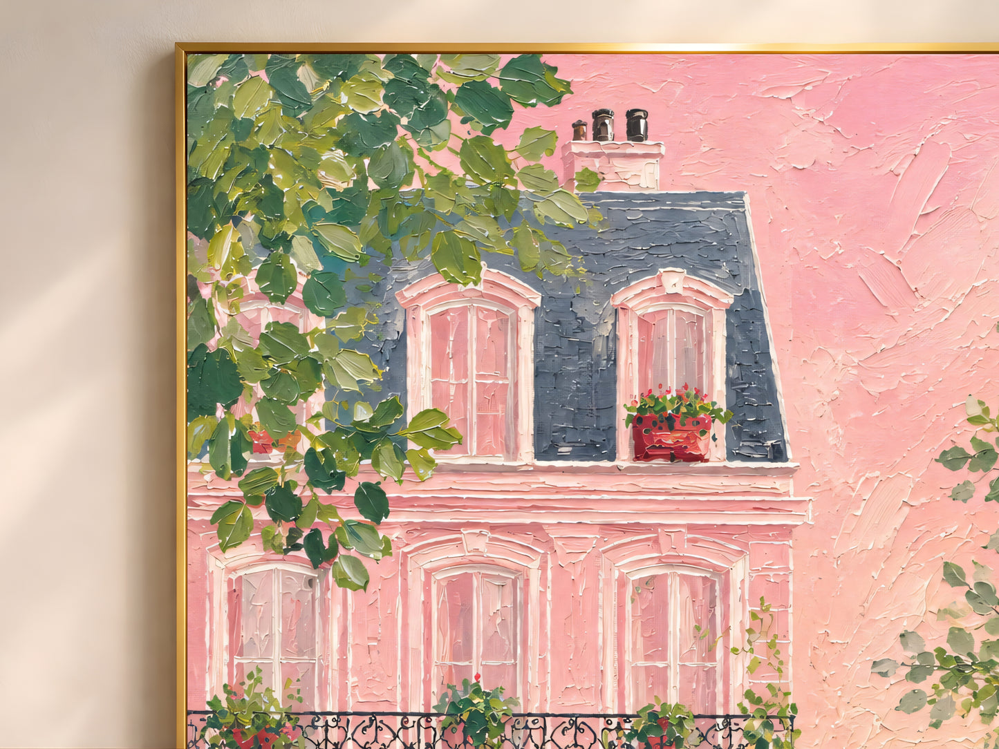 Close-up of impasto oil painting pink Parisian Haussmann building wall art in a gold frame showing flower boxes, iron balconies, red door, and lush green tree detail

