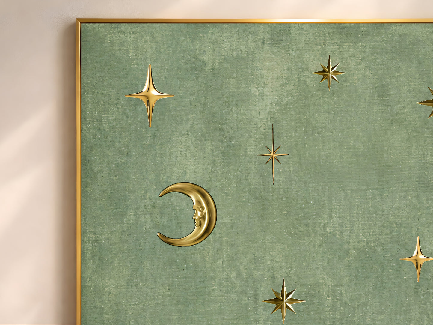 Close-up of vintage celestial moon and stars wall art in a thin gold frame, gold crescent moon and stars on sage green