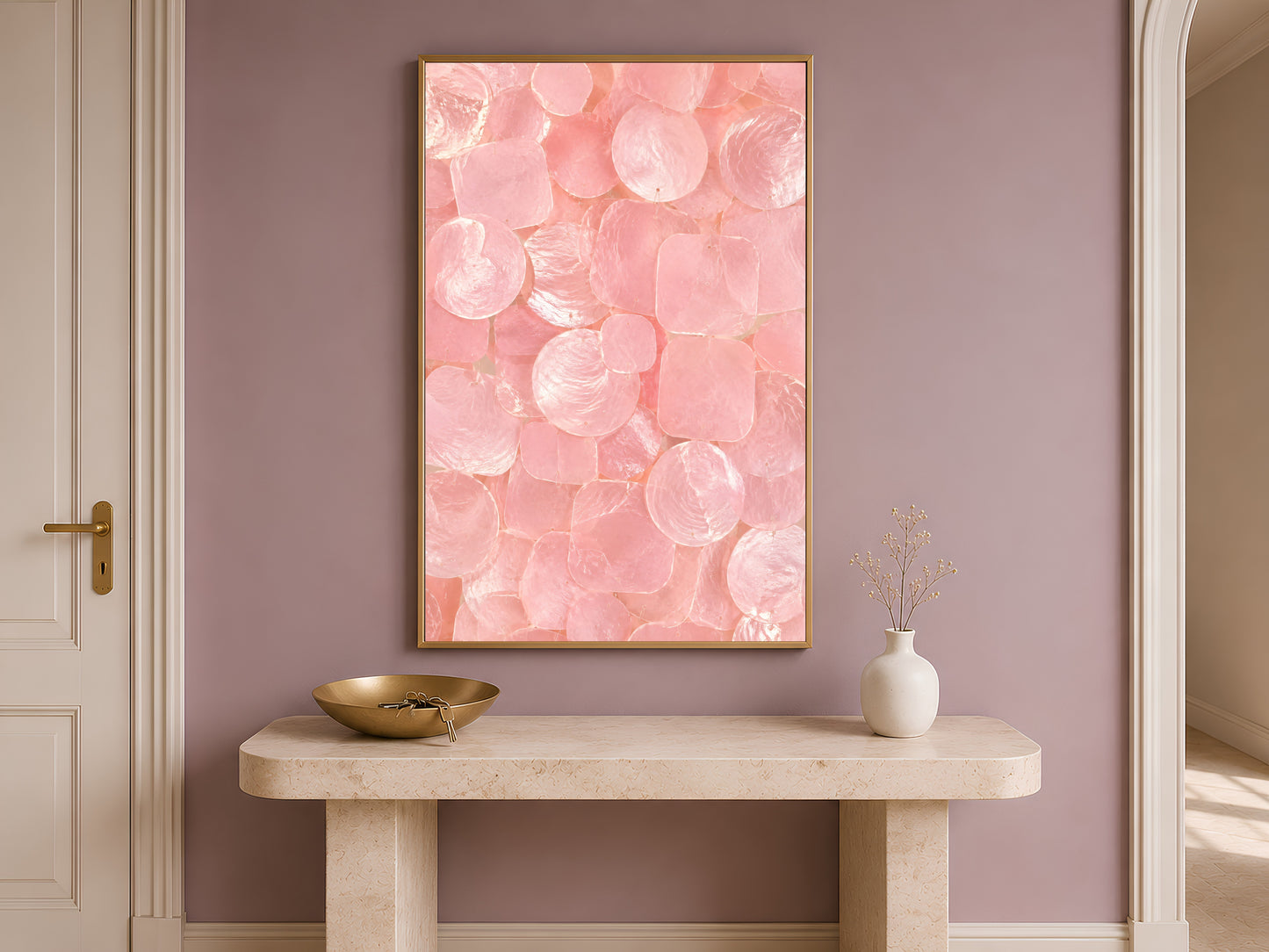 Pink capiz shell print in a gold frame hung above a console table in a warm-toned entryway.
