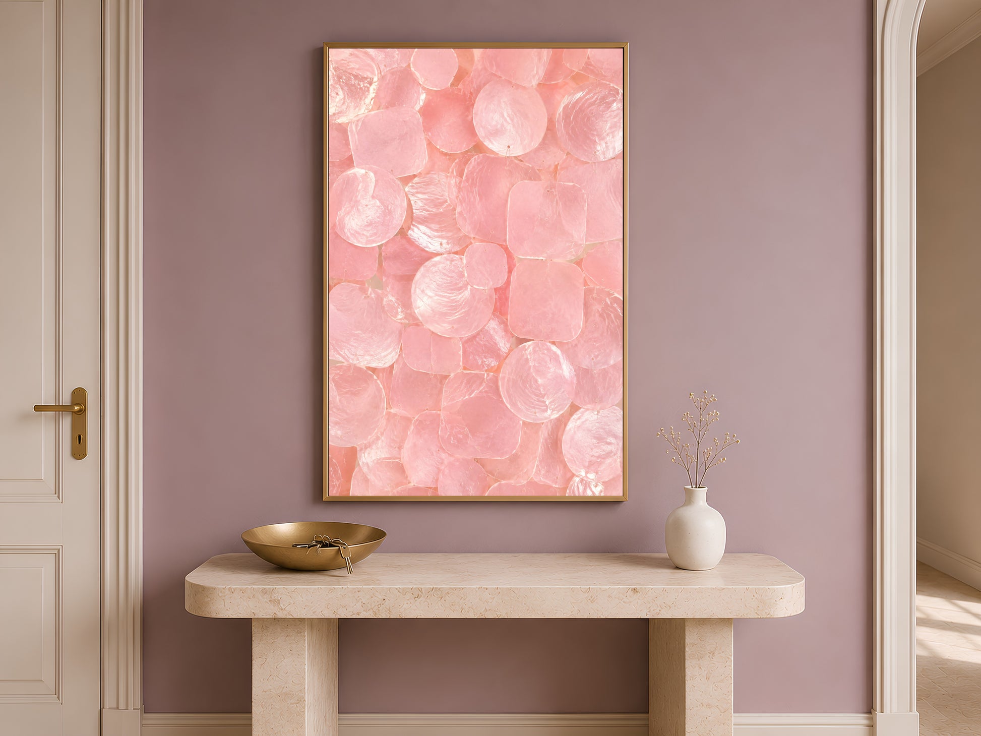 Pink capiz shell print in a gold frame hung above a console table in a warm-toned entryway.
