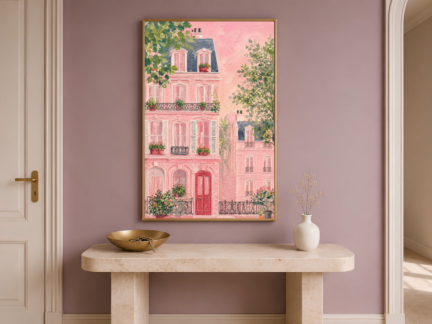 Impasto pink Parisian building wall art in a gold frame above a travertine console with a cream vase against a dusty mauve wall in a warm minimal entryway

