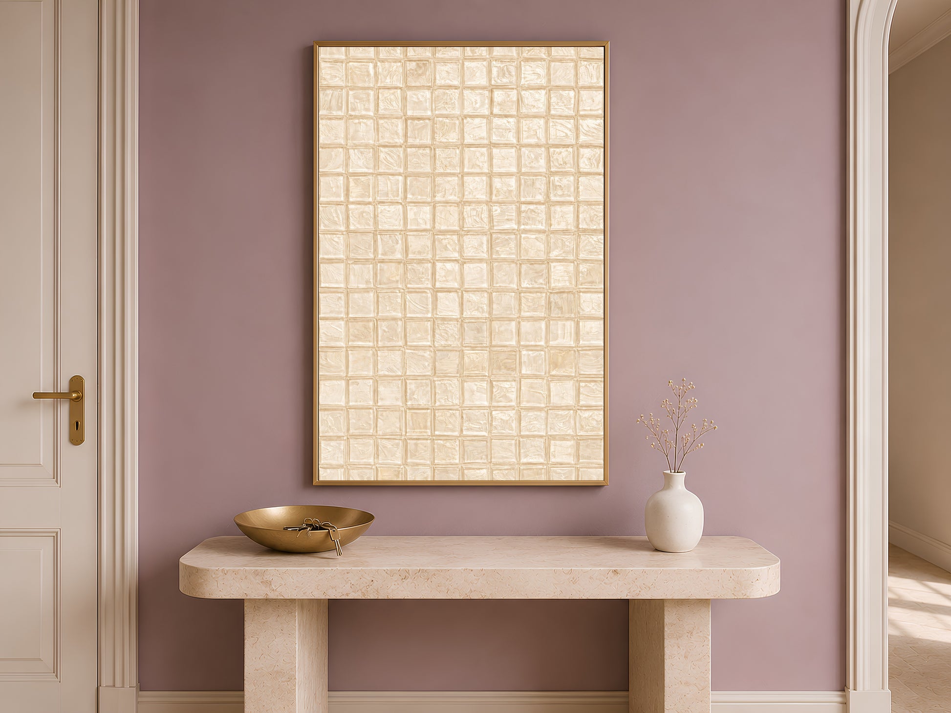 Warm beige mosaic tile wall art in a gold frame above a travertine console with cream ceramic vessels in a warm minimal entryway with dusty mauve wall