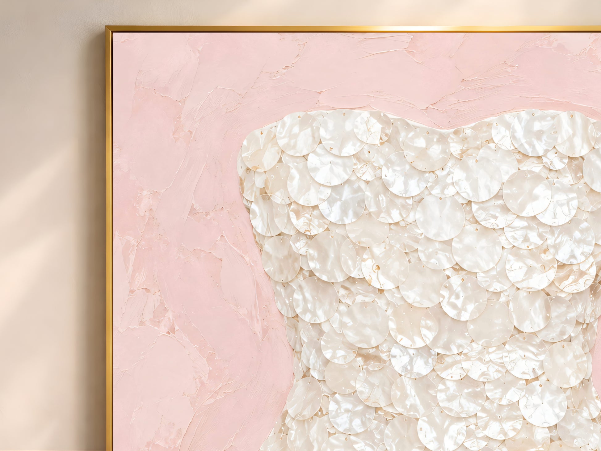 Blush pink mother of pearl wall art framed in gold, styled above a cream sofa in a bright living room.