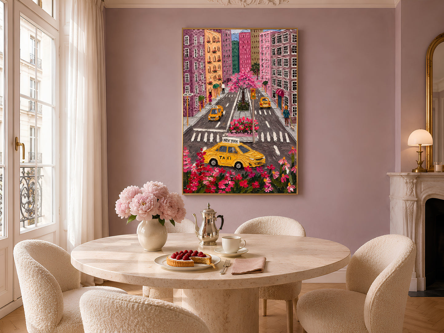 Colorful NYC taxi aerial print in gold frame above round dining table with pink flowers and neutral chairs
