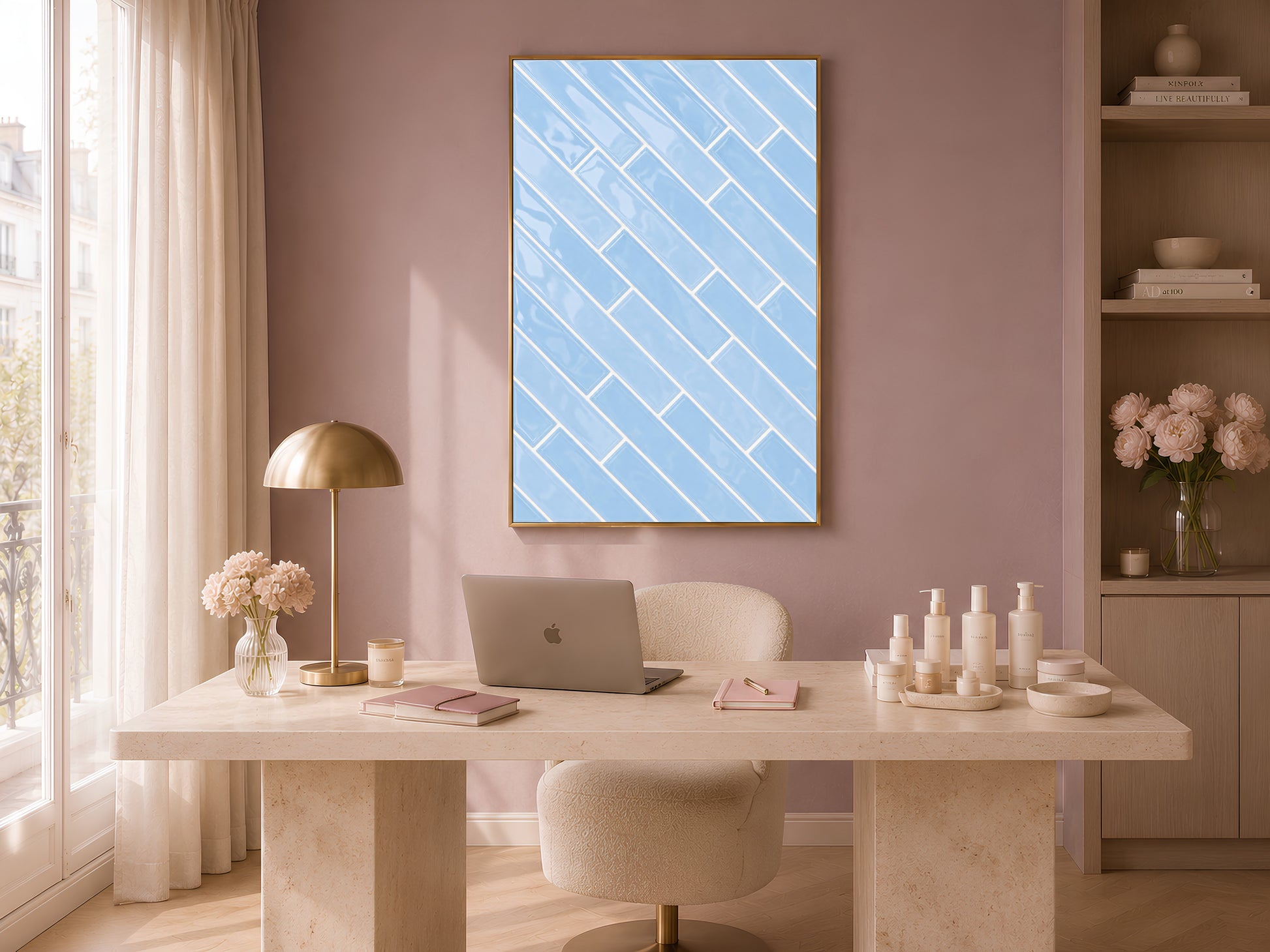 Blue herringbone tile wall art print in a gold frame above a stone desk in a soft pink room with a brass lamp and ceramic bottles
