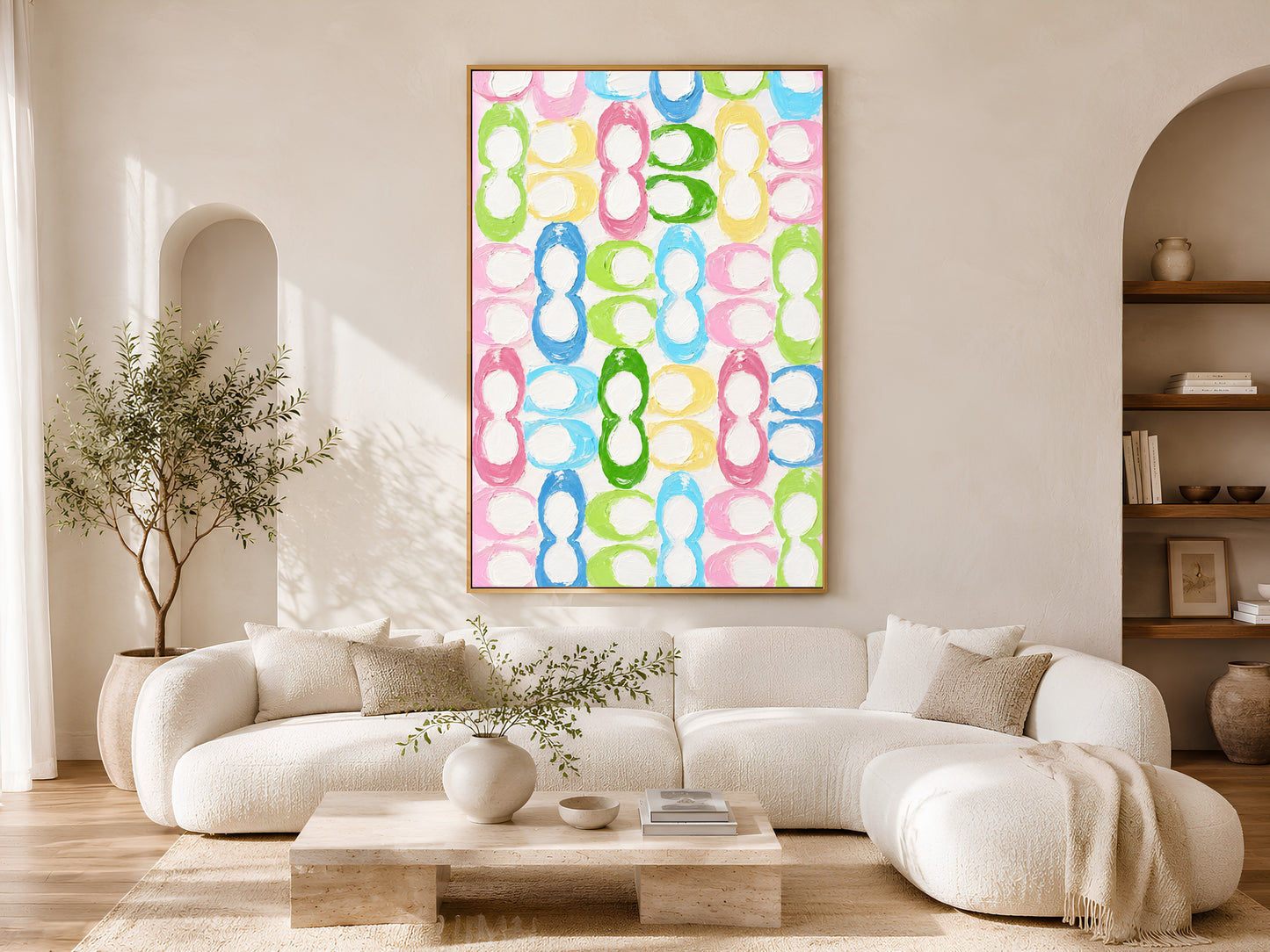 Colorful retro loop pattern wall art in gold frame in bright minimalist living room with white sofa and olive tree
