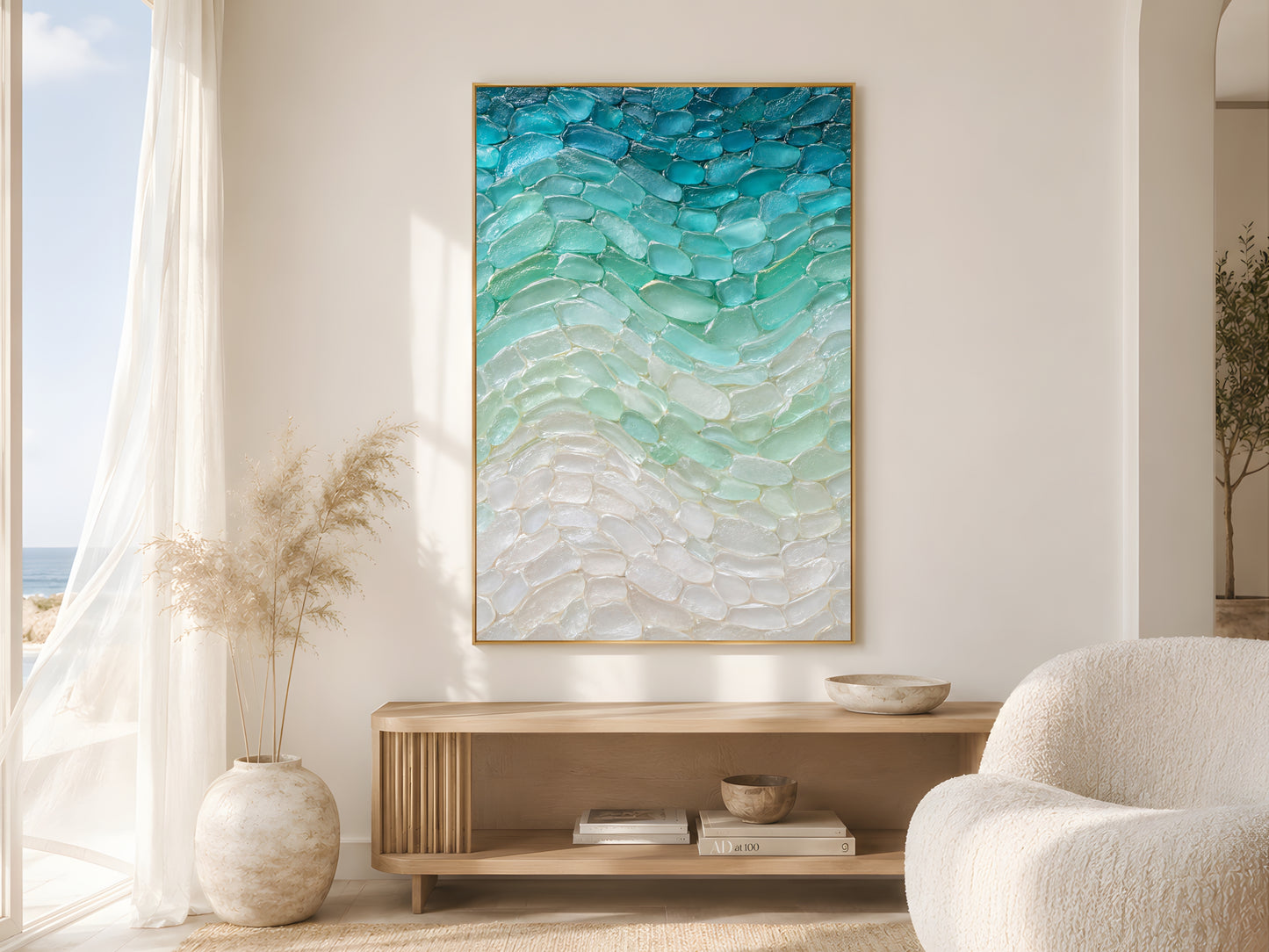 Sea glass teal wave print in wood frame in bright coastal living room with pampas grass and cream armchair