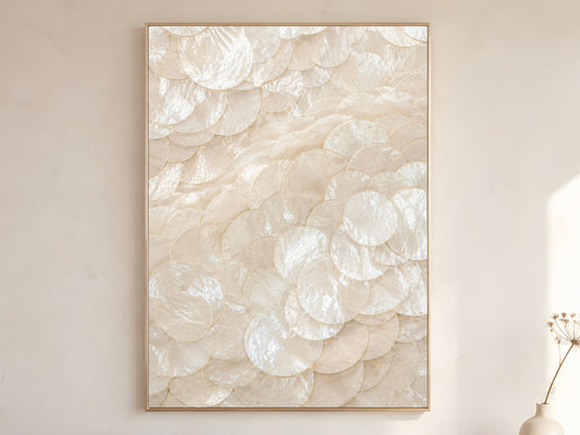 Capiz shell swirl spiral wall art print in gold frame displayed on warm white living room wall showing sweeping vortex pattern of pearlescent ivory shell discs with soft natural light

