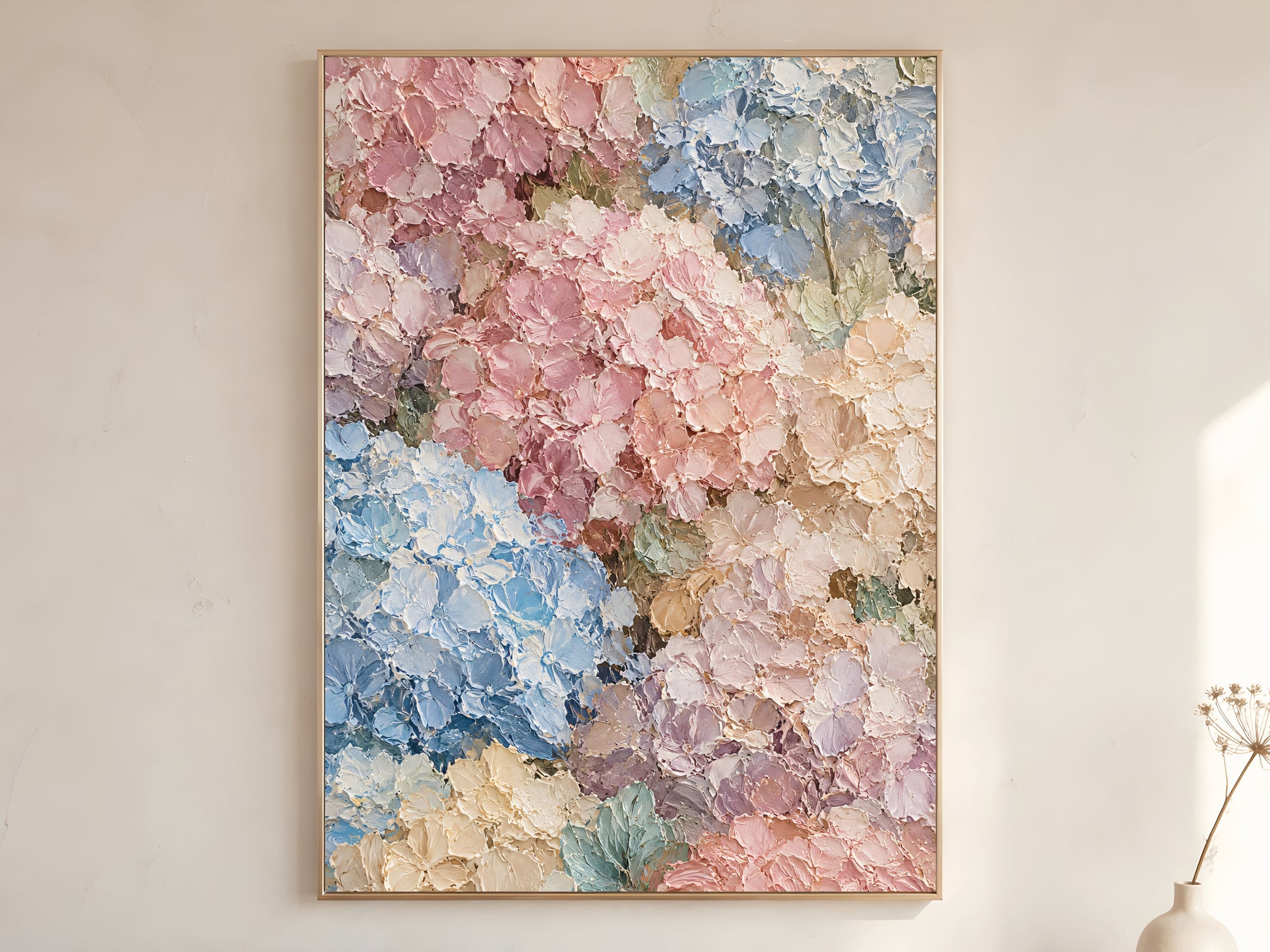 Pastel hydrangea impasto oil painting print in a thin gold frame on a warm white wall with a dried stem in a Scandinavian living room
