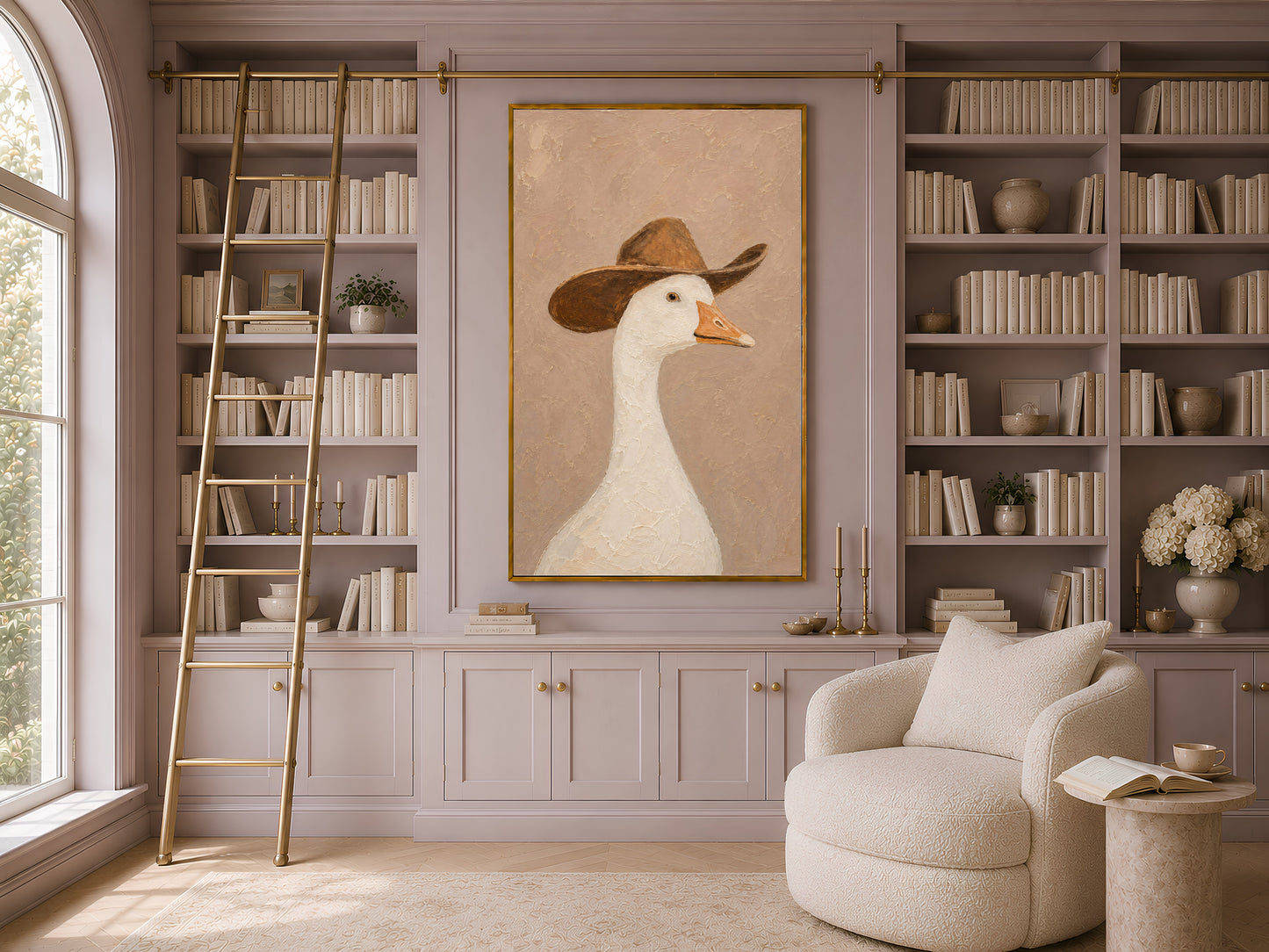 Framed silly goose cowboy art in a classic home library with built-in bookshelves, a ladder, and a cream armchair under large windows
