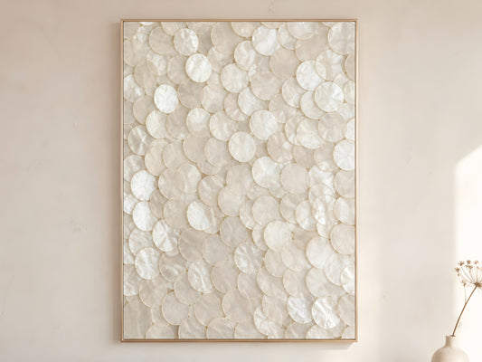 Pearlescent capiz shell wall art print in gold frame displayed on warm white living room wall with soft natural light and dried botanicals

