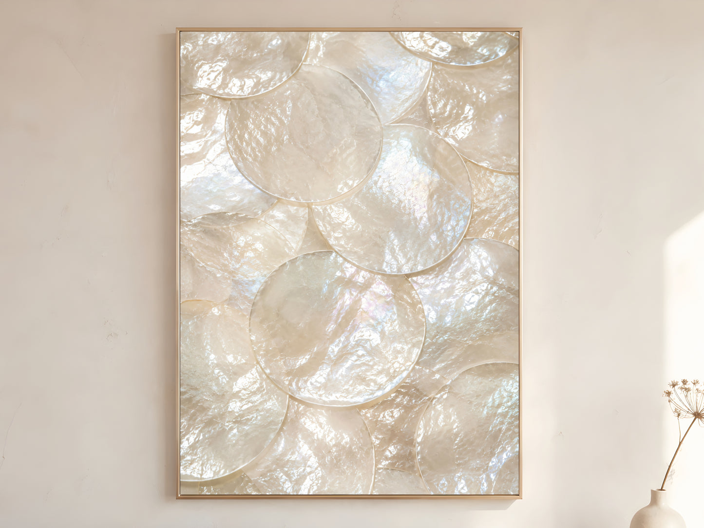 Mother of pearl iridescent shell wall art print in gold frame displayed on warm white living room wall showing large overlapping pearl white shell discs with rainbow shimmer
