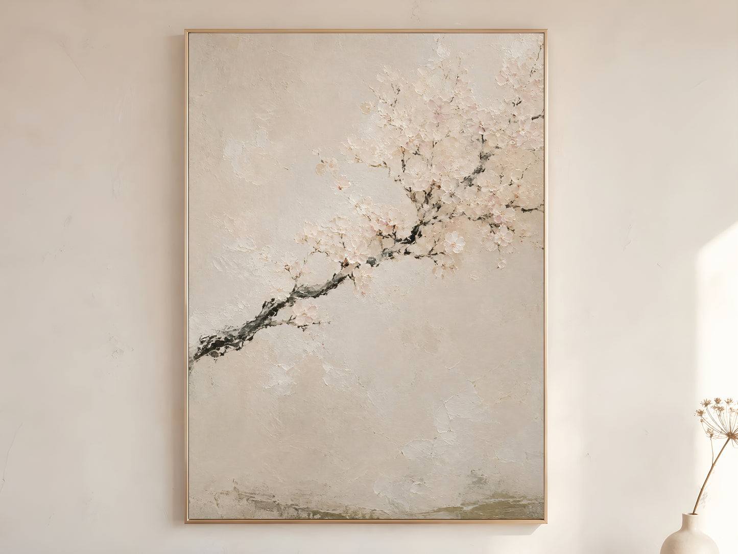 Japandi cherry blossom impasto oil painting print in a thin gold frame on a warm white wall with a dried stem in a minimal Scandinavian living room
